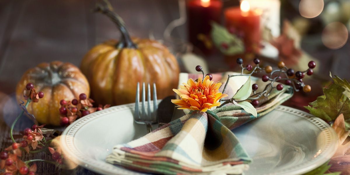 Autumn place setting with decorative pumpkins, candles and berries