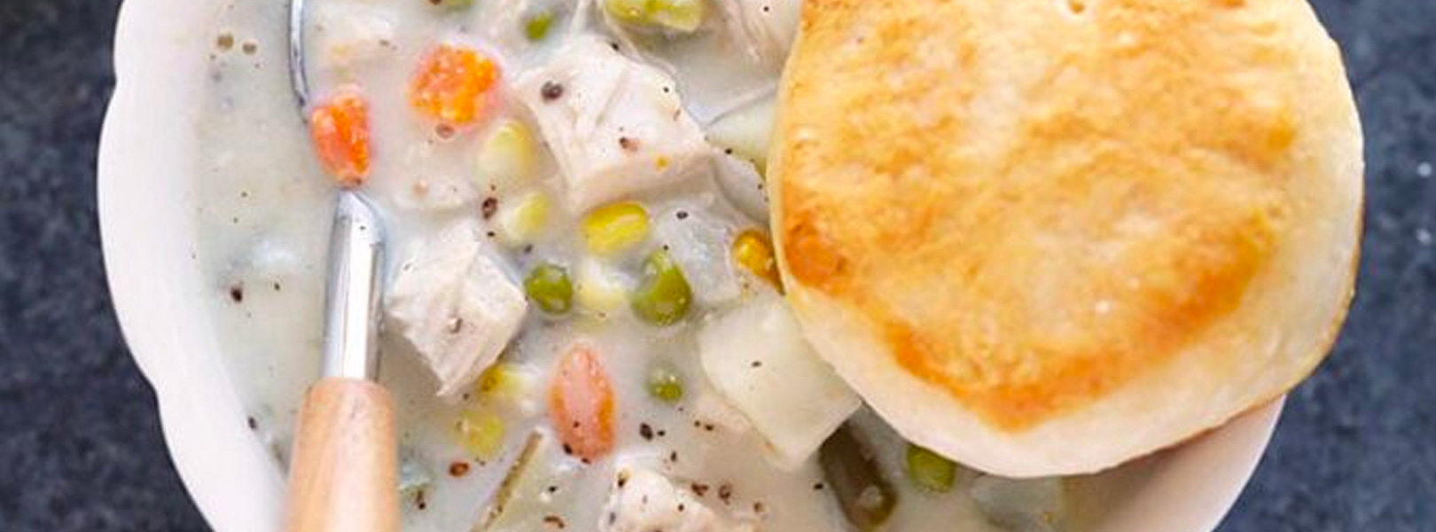 A bowl of chicken pot pie soup and biscuit