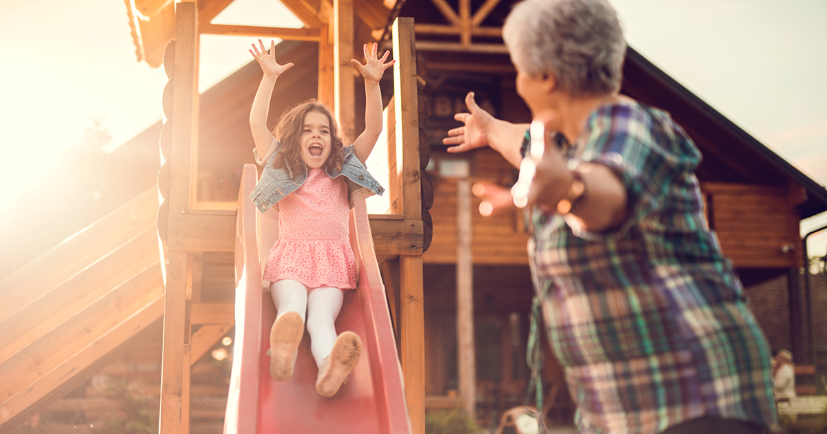 Grandmother playing with her granddaughter who is coming down the slide