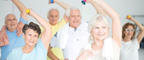 senior citizens raising dumbbells overhead in fitness class