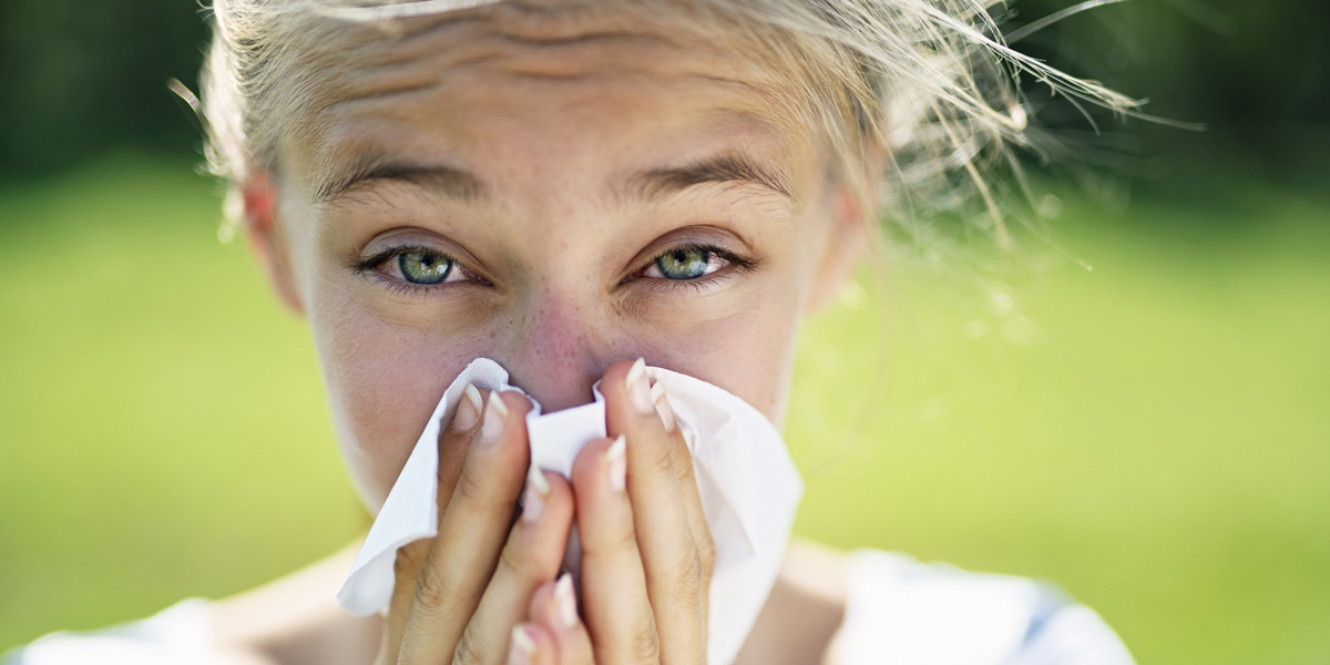 Teenager with allergies blowing her nose