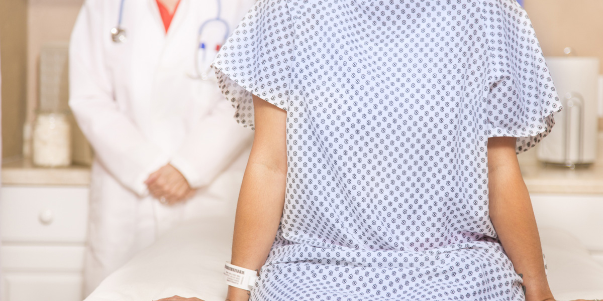 Woman sitting on exam table wearing medical gown