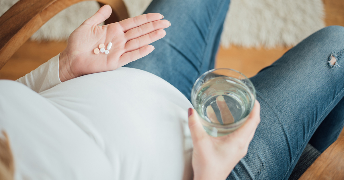 Close up of pregnant women holding pills in her hand