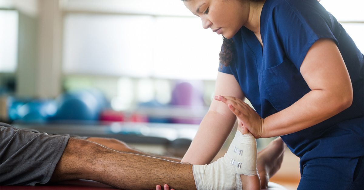 Physical therapist working on a man's taped up ankle