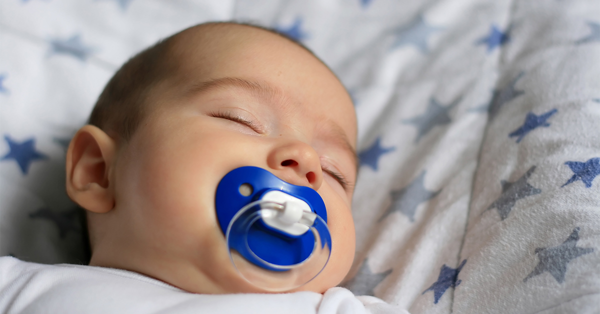 Newborn sleeping on back with pacifier in his mouth